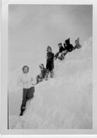 Six people are positioned on a very tall snow bank